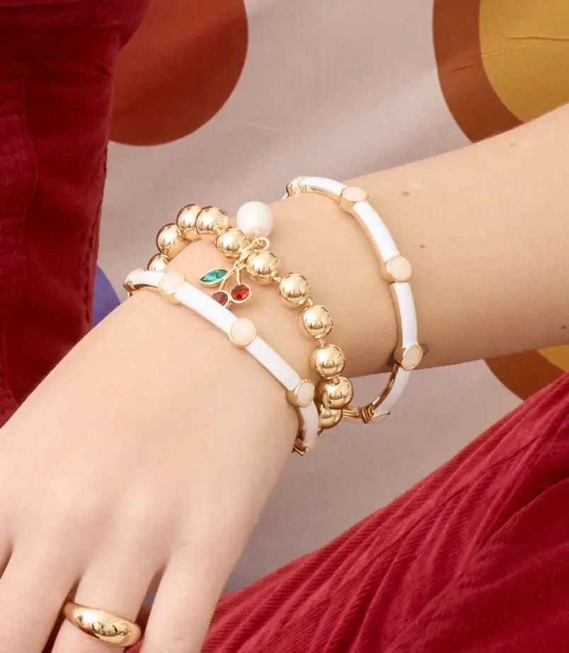 Model wearing Gold heart jewelry leaning against the wall