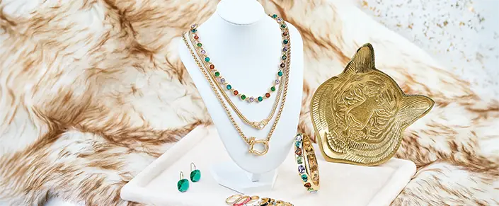 Gold jewelry collection with layered necklaces, colorful gemstones, earrings, bracelets, and rings